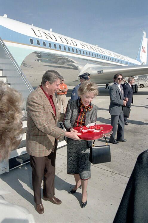 C27324-11, President Reagan giving Nancy Reagan a box of chocolates for Valentine's day on arri…